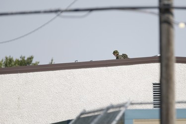 A sniper sits on a school roof in Neepawa, , Man., on Thursday, August 30, 2018 as the RCMP emergency response unit searches for an alleged suspect in the shooting of a RCMP officer in Onanole, Man. THE CANADIAN PRESS/John Woods