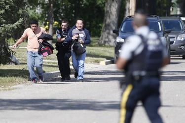 Two men are evacuated in Neepawa, Man., on Thursday, August 30, 2018 as the RCMP emergency response unit moves in on a home as they search for an alleged suspect in the shooting of a RCMP officer in Onanole, Man. THE CANADIAN PRESS/John Woods