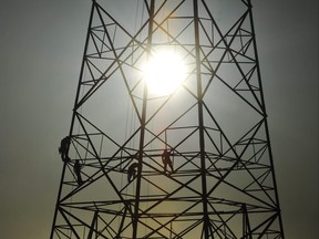 The sun rises behind a hydro tower dotted with workers
ED KAISER/Postmedia Network Files