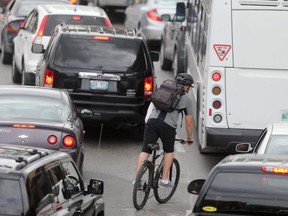 A cyclist in traffic in Winnipeg, Tuesday, July 24, 2018. Chris Procaylo/Winnipeg Sun