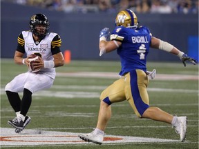 Hamilton Tiger-Cats QB Jeremiah Masoli (left) looks for a receiver as Winnipeg Blue Bombers LB Adam Bighill tracks him during CFL action in Winnipeg on Fri., Aug. 10, 2018. Bighill has a new three-year deal with the Bombers it was announced Tuesday, Jan. 15, 2019. Kevin King/Winnipeg Sun/Postmedia Network