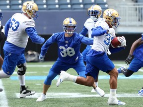 Winnipeg Blue Bombers linebacker Ian Wild (centre) gets a hand on running back Andrew Harris during practice on Tuesday.