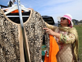 A woman sets up garnents at Jinnah Park in south Winnipeg on Sunday, ahead of a celebration to mark Pakistan's Independence Day.