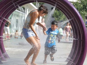A pair of Winnipeggers cool down at the City of Winnipeg spray pad at Central Park. Winnipeg Sun file