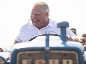 Ontario Premier Doug Ford sits on a Ford tractor as he plows a furrow at the International Plowing Match in Pain Court, Ont. (The Canadian Press)