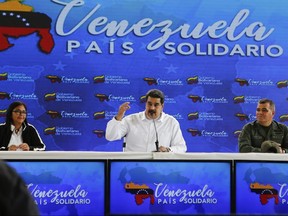 In this photo released by the Miraflores Press Office, Venezuela's President Nicolas Maduro, centre, speaks as he is accompanied by Venezuela's Vice President Delcy Rodriguez, left, and Defence Minister Vladimir Padrino, right, during a meeting with Colombian citizens that reside in Venezuela, in Caracas, Venezuela.