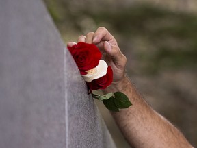 Stephen Thompson, from Atlanta, Ga., places roses on the monument as he remembers his father Ernest Thompson who perished in the crash of Swissair Flight 111 at a memorial service at Bayswater Beach, N.S. on Sunday, Sept. 2, 2018. Twenty years ago the passenger jet crashed in the Atlantic Ocean on Inner Rock Shoal, about 10 kilometres off the coast on Nova Scotia's South Shore, killing 229 people. THE CANADIAN PRESS/Andrew Vaughan ORG XMIT: XAV113
