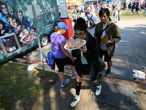 A woman chows down on pizza as she heads for the beer gardens to find a seat during ManyFest in downtown Winnipeg on Sun., Sept. 9, 2018. Kevin King/Winnipeg Sun/Postmedia Network