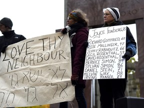 The names of the victims of the shooting at the Tree of Life Synagogue in Pittsburgh are held during a vigil against anti-Semitism and white supremacy at the Human Rights Monument in Ottawa on Sunday.