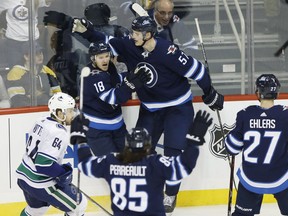Winnipeg Jets' Bryan Little (18), Tyler Myers (57), Mathieu Perreault (85) and Nikolaj Ehlers (27) celebrate Little's game winning goal against the Vancouver Canucks during third period NHL action in Winnipeg on Thursday, October 18, 2018. THE CANADIAN PRESS/John Woods ORG XMIT: JGW116