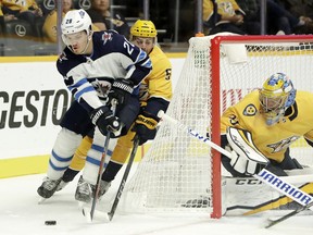 Winnipeg Jets center Jack Roslovic (28) brings the puck around the net as Nashville Predators defenseman Dan Hamhuis (5) and goaltender Pekka Rinne (35), of Finland, follow him during the first period of an NHL hockey game Thursday, Oct. 11, 2018, in Nashville, Tenn.