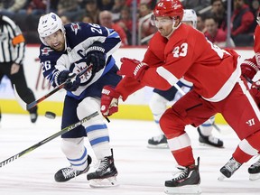 Winnipeg Jets right wing Blake Wheeler (26) shoots the puck into the corner against Detroit Red Wings center Darren Helm (43) during the first period of an NHL hockey game Friday, Oct. 26, 2018, in Detroit. (AP Photo/Duane Burleson)