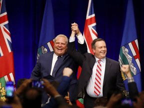 United Conservative Party Leader Jason Kenney and Ontario Premier Doug Ford cheer with supporters at an anti-carbon tax rally in Calgary, Friday, Oct. 5, 2018.