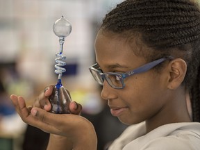 A young girl looks at a beaker during science class.
