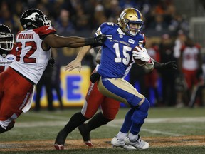 Winnipeg Blue Bombers quarterback Matt Nichols attempts to get out of the grasp of Calgary Stampeders' Ese Mrabure. (The Canadian Press)