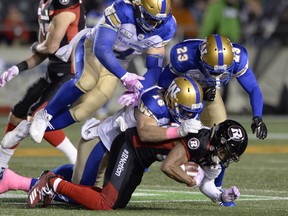 Winnipeg Blue Bombers defensive back Taylor Loffler (16), linebacker Adam Bighill (4) and defensive back Anthony Gaitor (23) bring down Ottawa Redblacks wide receiver Diontae Spencer during Friday's game in Ottawa. (THE CANADIAN PRESS)