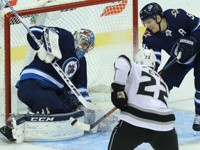 Winnipeg Jets centre Mark Scheifele (right) clears a loose puck from in front of goaltender Connor Hellebuyck before  Los Angeles Kings centre Trevor Lewis can get to it in Winnipeg on Tues., Oct. 9, 2018. (KEVIN KING/WINNIPEG SUN)