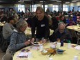 A volunteer serves Lawrence Beaulieu (left) and Donald Bacon during Siloam Mission's annual Thanksgiving meal in Winnipeg at lunchtime on Friday.