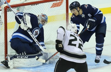 Winnipeg Jets centre Mark Scheifele (right) clears a loose puck from in front of goaltender Connor Hellebuyck before  Los Angeles Kings centre Trevor Lewis can get to it in Winnipeg on Tues., Oct. 9, 2018. Kevin King/Winnipeg Sun/Postmedia Network