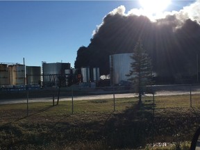 A passerby photographs the scene of a fire at an asphalt plant in the area of Saunders Street and Gunn Road in the R.M. of Springfield involving asphalt tanks, on Monday before Winnipeg Fire Paramedic Service and Springfield Fire Department crews arrived.