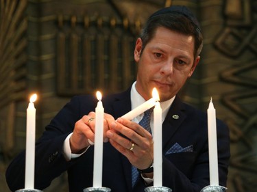 Mayor Brian Bowman lights a candle at a vigil for victims of a mass shooting on Saturday at a synagogue in Pittsburgh, at Congregation Shaarey Zedek in Winnipeg, on Tues., Oct. 30, 2018. Kevin King/Winnipeg Sun/Postmedia Network