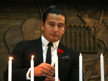 Provincial New Democrat Party leader Wab Kinew lights a candle at a vigil for victims of a mass shooting on Saturday at a synagogue in Pittsburgh, at Congregation Shaarey Zedek in Winnipeg, on Tues., Oct. 30, 2018. Kevin King/Winnipeg Sun/Postmedia Network