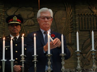 MP Jim Carr lights a candle at a vigil for victims of a mass shooting on Saturday at a synagogue in Pittsburgh, at Congregation Shaarey Zedek in Winnipeg, on Tues., Oct. 30, 2018. Kevin King/Winnipeg Sun/Postmedia Network