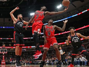 Justin Holidayof the Chicago Bulls rebounds over teammate Antonio Blakeney and Jonas Valanciunas #17 and Malachi Richardson of the Toronto Raptors at United Center on Saturday. (Photo by Jonathan Daniel/Getty Images)