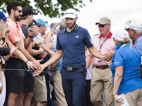Dustin Johnson, of the United States, greets fans as he walks onto the first hole during the Canadian Open at the Glen Abbey Golf Club in Oakville, Ont., Sunday, July 29, 2018. (THE CANADIAN PRESS/Nathan Denette)
