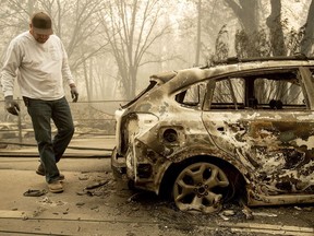 Eric England searches through a friend's vehicle on Pearson Rd. after the wildfire burned through Paradise, Calif., on Saturday, Nov. 10, 2018. Not much is left in Paradise after a ferocious wildfire roared through the Northern California town as residents fled and entire neighborhoods are leveled.