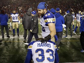Winnipeg Blue Bombers' Andrew Harris (33) iis consoled by teammate Thomas Miles after losing to the Calgary Stampeders following the CFL West Final football game in Calgary, Sunday, Nov. 18, 2018.THE CANADIAN PRESS/Jeff McIntosh