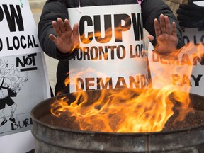 Striking Canada Post workers keep their hands warm as they picket at the South Central sorting facility in Toronto on Tuesday, November 13, 2018.