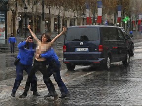 French police officers apprehend a topless protestor who ran toward the motorcade of President Donald Trump who was headed on the Champs Elysees to an Armistice Day Centennial Commemoration at the Arc de Triomphe, Sunday Nov. 11, 2018, in Paris.