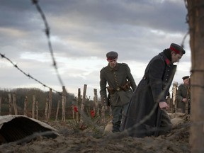 In this Dec. 20, 2014 file photo, re-enactors dressed in World War I German uniforms walk into a reconstructed trench during a re-enactment in Ploegsteert, Belgium.