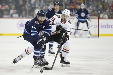 Winnipeg Jets' Blake Wheeler (26) and Chicago Blackhawks' Brendan Perlini (11) chase down a loose puck during second period NHL action in Winnipeg on Thursday, November 29, 2018. THE CANADIAN PRESS/John Woods