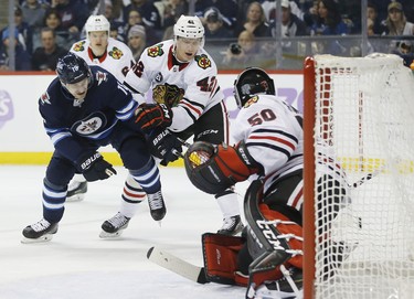 Winnipeg Jets' Bryan Little (18) drives for the net as Chicago Blackhawks goaltender Corey Crawford (50) saves his shot and Hawks' Gustav Forsling (42) defends during second period NHL action in Winnipeg on Thursday, November 29, 2018. THE CANADIAN PRESS/John Woods