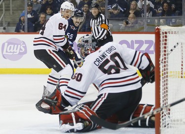 Winnipeg Jets' Mark Scheifele (55) looks on as Chicago Blackhawks goaltender Corey Crawford (50) saves his backhander and Hawks' David Kampf (64) defends during second period NHL action in Winnipeg on Thursday, November 29, 2018. THE CANADIAN PRESS/John Woods