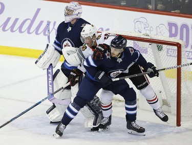 Winnipeg Jets' Ben Chiarot (7) keeps Chicago Blackhawks' Jonathan Toews (19) under control in front of Jets goaltender Connor Hellebuyck (37) during third period NHL action in Winnipeg on Thursday, November 29, 2018. THE CANADIAN PRESS/John Woods