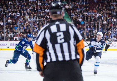 Winnipeg Jets' Andrew Copp (9) reaches for the puck while being watched by Vancouver Canucks' Markus Granlund (60), of Finland, during the first period of an NHL hockey game in Vancouver, on Monday November 19, 2018. THE CANADIAN PRESS/Darryl Dyck
