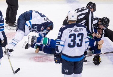 Vancouver Canucks' Antoine Roussel, right, of France, is restrained as he and Winnipeg Jets' Brandon Tanev, left, fight during the second period of an NHL hockey game in Vancouver, on Monday November 19, 2018. THE CANADIAN PRESS/Darryl Dyck