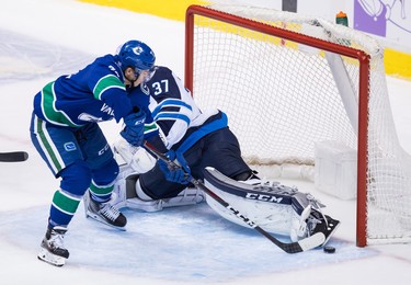 Vancouver Canucks' Nikolay Goldobin, front left, of Russia, scores against Winnipeg Jets goalie Connor Hellebuyck during the second period of an NHL hockey game in Vancouver, on Monday November 19, 2018. THE CANADIAN PRESS/Darryl Dyck