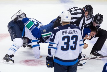 Vancouver Canucks' Antoine Roussel, right, of France, is restrained as he and Winnipeg Jets' Brandon Tanev, left, fight during the second period of an NHL hockey game in Vancouver, on Monday November 19, 2018. THE CANADIAN PRESS/Darryl Dyck