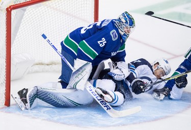 Winnipeg Jets' Adam Lowry, right, crashes into Vancouver Canucks goalie Jacob Markstrom, of Sweden, during the second period of an NHL hockey game in Vancouver, on Monday November 19, 2018. THE CANADIAN PRESS/Darryl Dyck