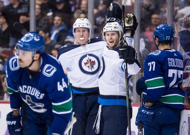 Winnipeg Jets' Patrik Laine, back left, of Finland, and Kyle Connor, back right, celebrate Laine's second goal as Vancouver Canucks' Erik Gudbranson (44) and Nikolay Goldobin, of Russia, look on during the third period of an NHL hockey game in Vancouver, on Monday November 19, 2018. THE CANADIAN PRESS/Darryl Dyck