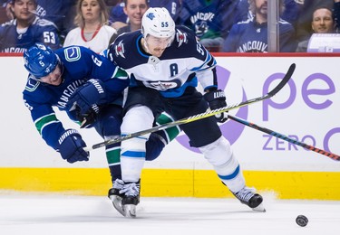 Vancouver Canucks' Derrick Pouliot (5) checks Winnipeg Jets' Mark Scheifele (55) during the third period of an NHL hockey game in Vancouver, on Monday November 19, 2018. THE CANADIAN PRESS/Darryl Dyck