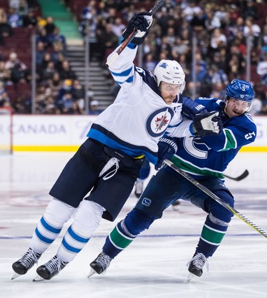 Winnipeg Jets' Blake Wheeler, left, is checked by Vancouver Canucks' Derrick Pouliot during the third period of an NHL hockey game in Vancouver, on Monday November 19, 2018. THE CANADIAN PRESS/Darryl Dyck