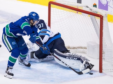Vancouver Canucks' Nikolay Goldobin, front left, of Russia, scores against Winnipeg Jets goalie Connor Hellebuyck during the second period of an NHL hockey game in Vancouver, on Monday November 19, 2018. THE CANADIAN PRESS/Darryl Dyck ORG XMIT: VCRD120