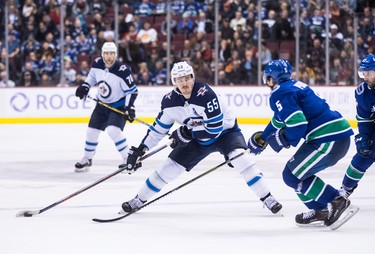 Winnipeg Jets' Mark Scheifele (55) shoots the puck past Vancouver Canucks' Derrick Pouliot (5) during the first period of an NHL hockey game in Vancouver, on Monday November 19, 2018. THE CANADIAN PRESS/Darryl Dyck
