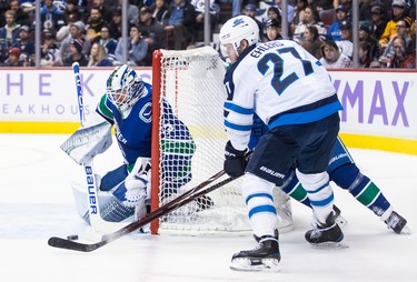 Winnipeg Jets' Nikolaj Ehlers (27), of Denmark, attempts a wrap-around on Vancouver Canucks goalie Jacob Markstrom, left, of Sweden, as Ben Hutton, back right, defends during the first period of an NHL hockey game in Vancouver, on Monday November 19, 2018. THE CANADIAN PRESS/Darryl Dyck