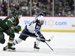 Minnesota Wild's Jonas Brodin (25), of Sweden, and Winnipeg Jets' Mathieu Perreault (85) go after the puck during the second period of an NHL hockey game Friday, Nov. 23, 2018, in St. Paul, Minn.